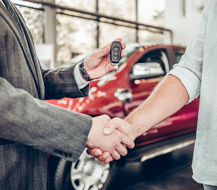 salesperson showing customers a new car at a dealership