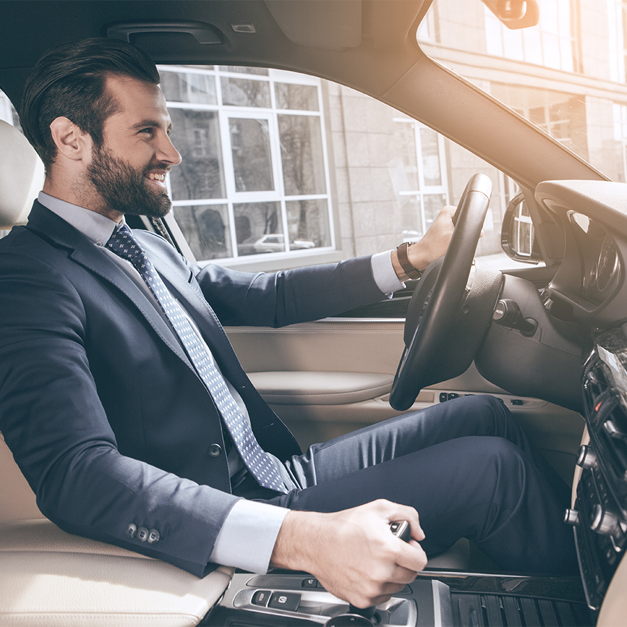 Man in suit sitting in vehicle smiling.