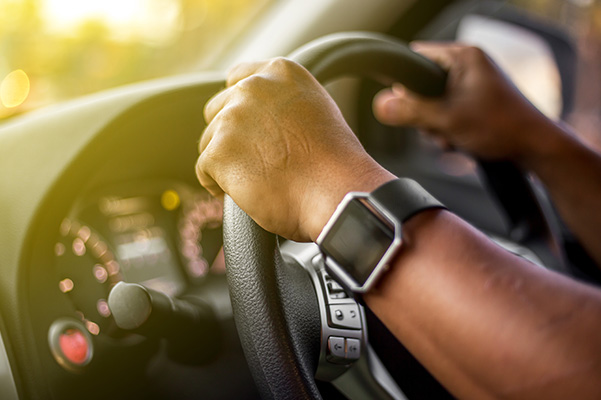 Man who wearing smart watch is driving vehicle while working or going to somewhere with the flare from the outside.