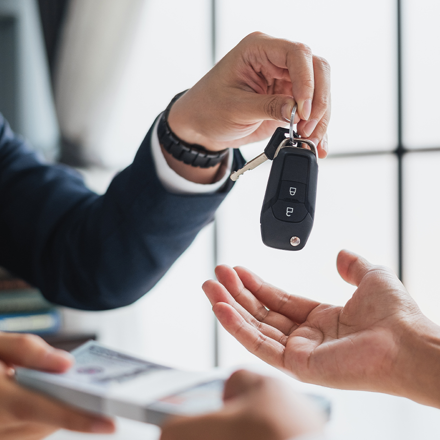 Closeup hand giving a car key and money for loan credit financial, lease and rental concept