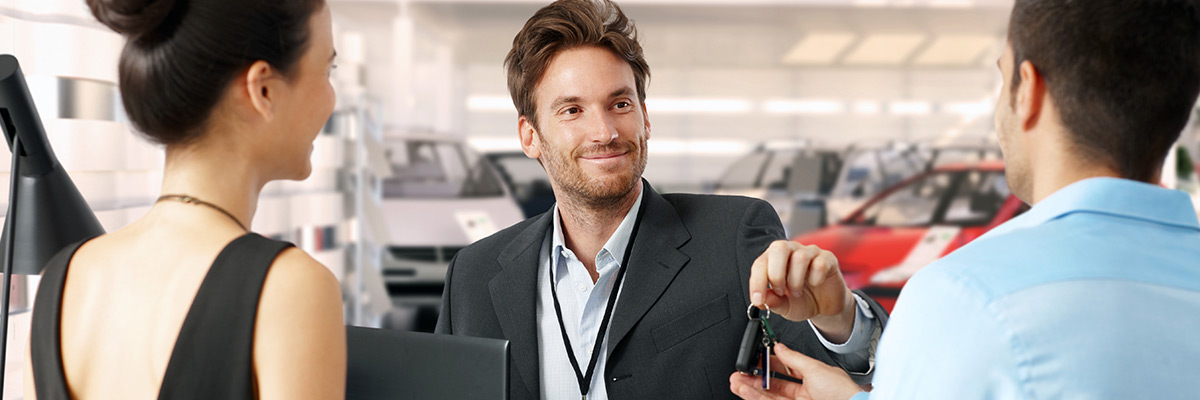 Dealership employee handing car key to a customer