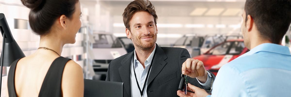 Close up of a car key being handed from one person to another in dealership