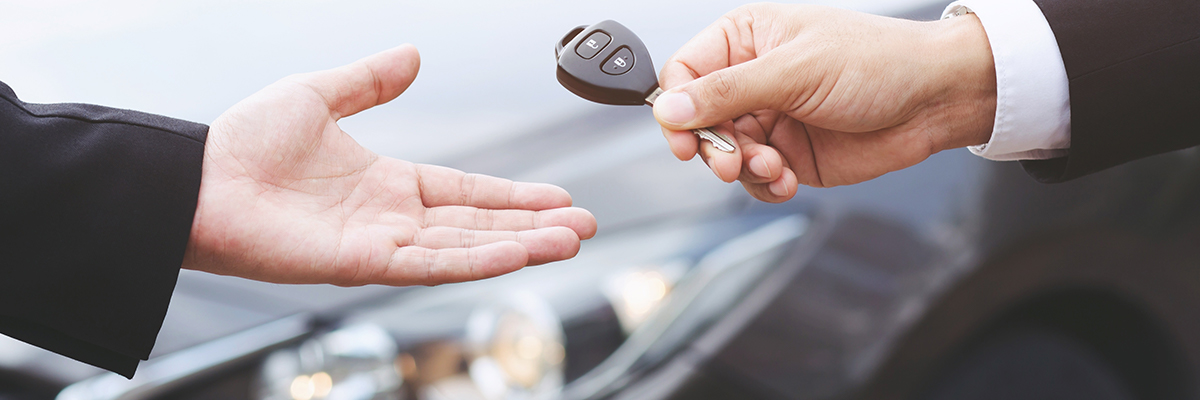 Close up of a car key being handed from one person to another