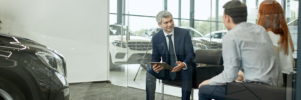 Dealership salesman talking to couple in showroom office