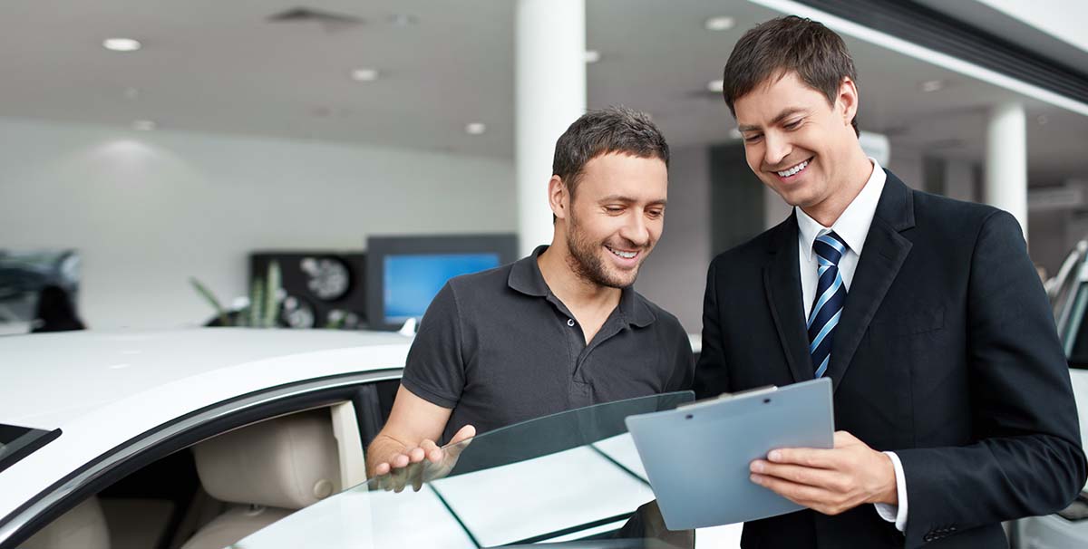 Two people looking at a clipboard at a car dealership