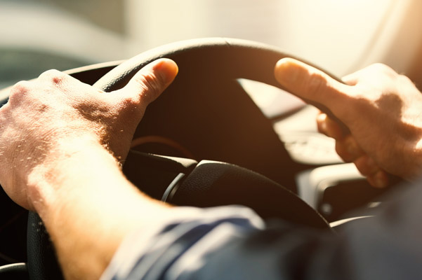 Close up of hands on steering wheel.