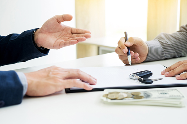 Car keys sitting on a pile of paperwork with a credit card and calculator blurred out in the background