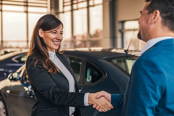Dealership employee smiling and shaking hand of satisfied customer