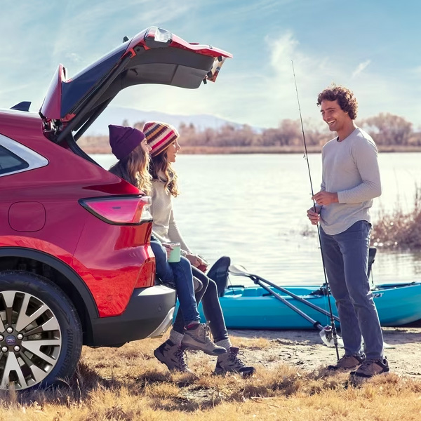 Person holding a dog standing in front of a parked Ford SUV