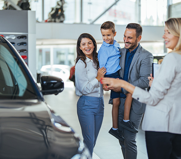 Happy family looking at a used vehicle in the dealership