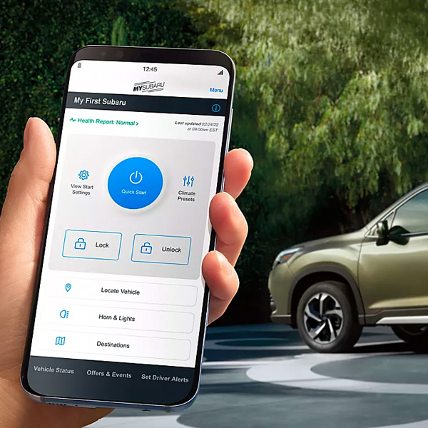 A hand holding a smart phone displaying the MySubaru mobile app