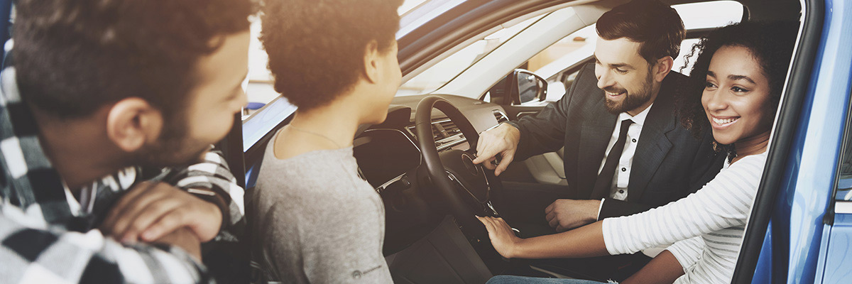 Family looking at a car with Salesman showing the interior