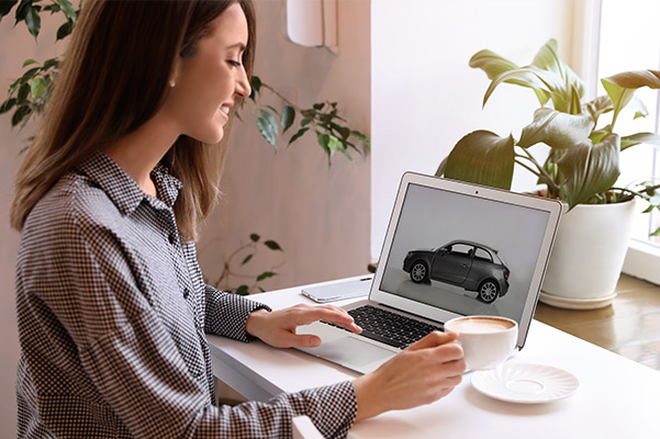 Woman looking at laptop smiling with image of car on it