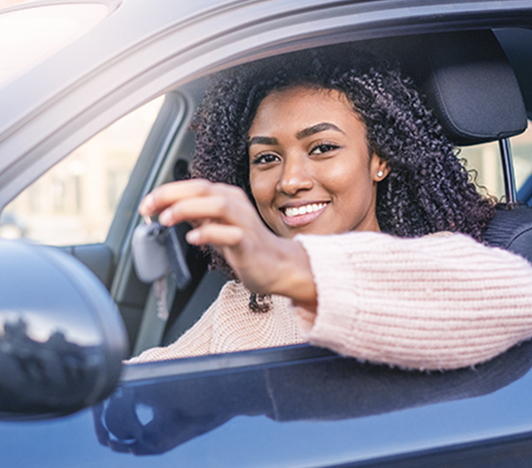 Dealership employee smiling shaking hands with satisfied customer.