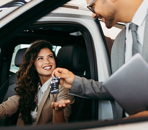 Dealership employee smiling shaking hands with satisfied customer.