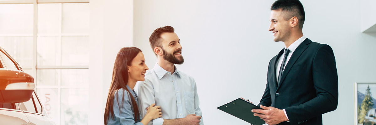 Happy couple talking to salesman in showroom