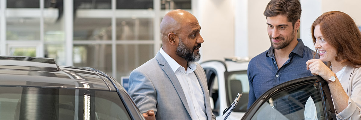 couple looking at vehicle in dealship with salesman