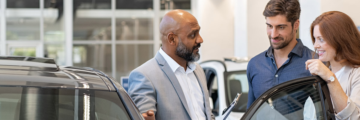 Customers and salesman checking out a car on the showroom floor