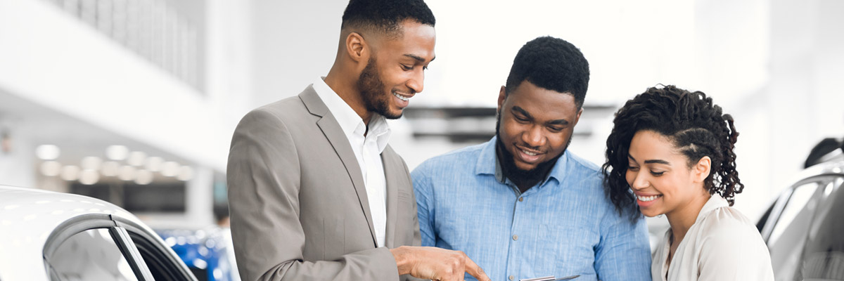 couple speaking with a salesman at a car dealership