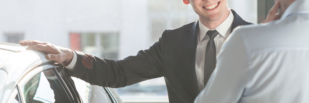 Dealership employee showing customers cars on showroom floor.